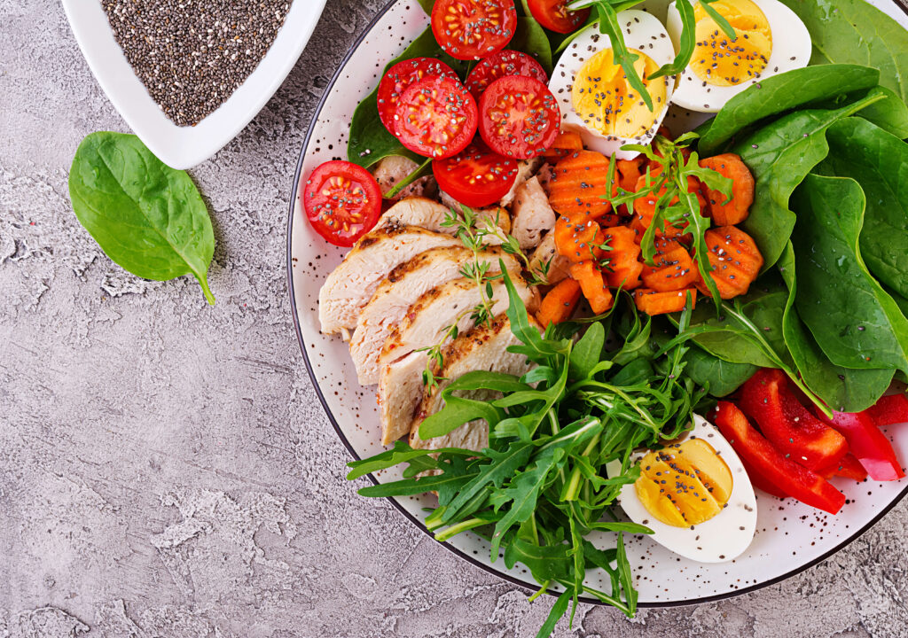 plate-with-keto-diet-food-cherry-tomatoes-chicken-breast-eggs-carrot-salad-with-arugula-spinach-keto-lunch-top-view